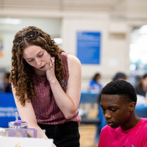 A School of Medicine student help a young member of the community during a community health fair.