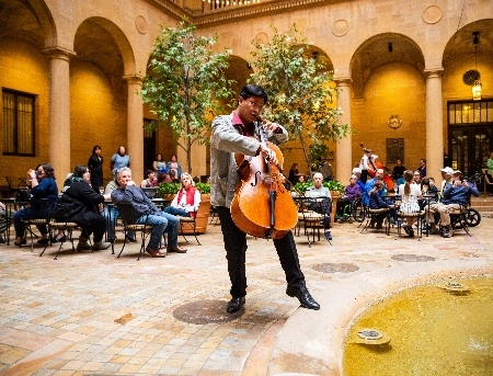 A person playing a musical instrument while others site at tables.