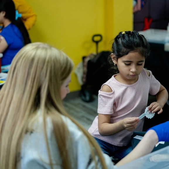 A medical student helping a child at a School of Medicine community event.