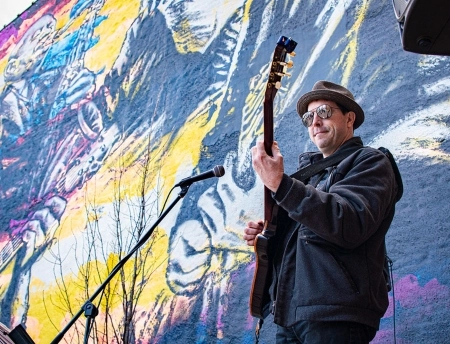 A guitarist playing in front of a mural in downtown St. Joseph (credit: St. Joseph Chamber of Commerce).