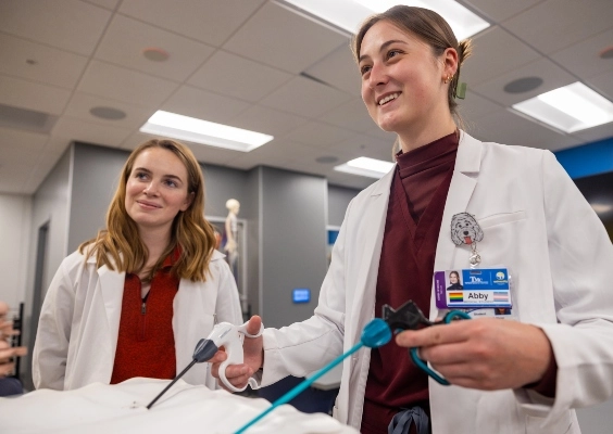 Two M.D. students practice a procedure in the simulation lab.