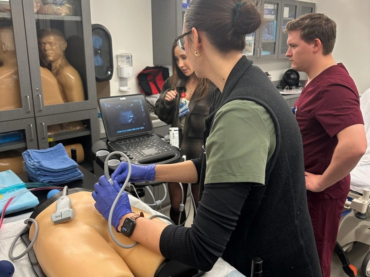 Two medical students and an instructor practice ultrasounds in the simulation center.