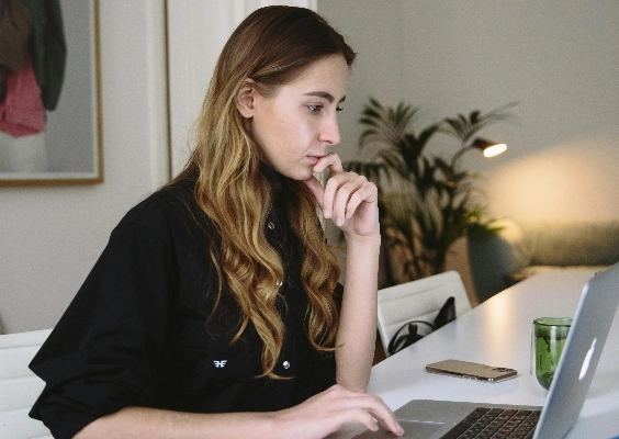 A graduate students reads admission requirements on her laptop at home.