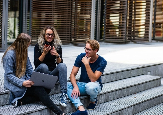 Graduate students talking on the steps of a building.