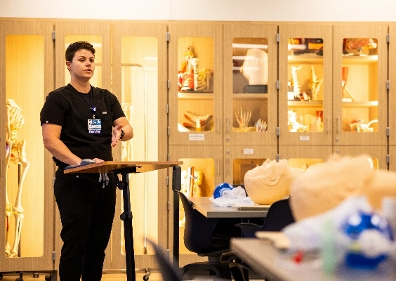 A medical school educator gives a lecture in front of a class.