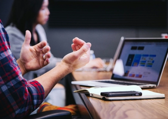 Closeup of a student talking with their hands in class.