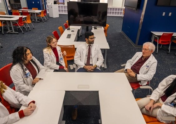 School of Medicine students sitting around a conference table talking with faculty.