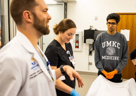 School of Medicine students talk with a faculty member in the simulation lab.