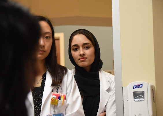 A medical student watches as a faculty member demonstrates a procedure.