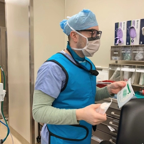 An anesthesiology resident carrying supplies during a procedure.