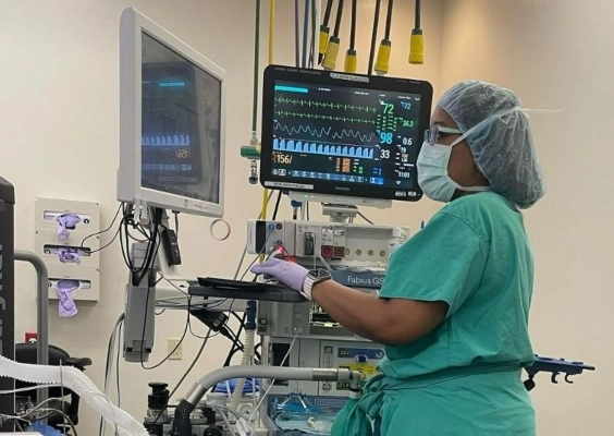 An anesthesiology resident monitors a patient's vitals during a procedure.