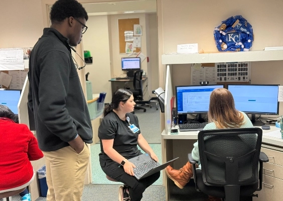 Family Medicine students and faculty talking around a hospital workstation.