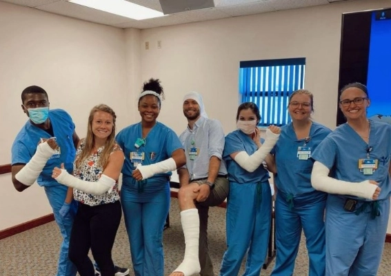 Family medicine residents posing for a group photo with casts on their arms and legs after completing a cast workshop.