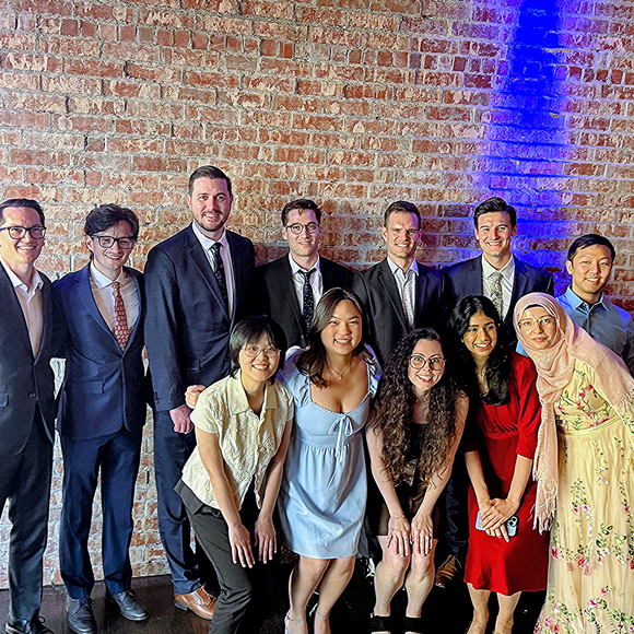 Family medicine residents and faculty stand around a hospital workstation talking about a patient case.