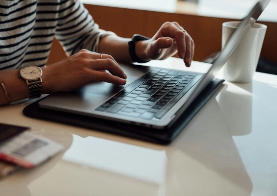 A person's hands as they type on a laptop.