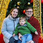 Madison, husband and child with a holiday backdrop