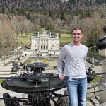 Portrait of Bryce Lord in standing in front of a large, classical estate.