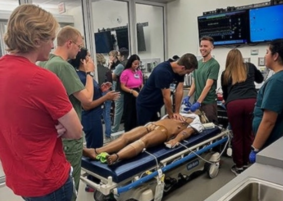 Emergency Medicine residents participate in simulation training around a hospital bed.