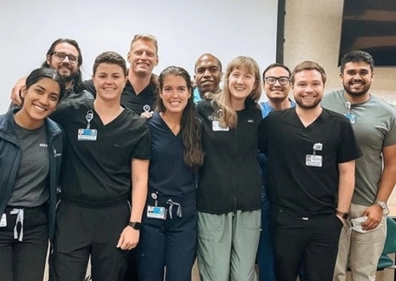 A group of emergency medicine residents pose for a photo in their scrubs. 