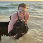 Portrait of Kathryn Finneran and her dog at the beach.