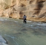 Photo of Aaron Hassad standing inside a stream within a canyon.