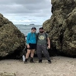 Portrait of Connor Muolo with her husband standing on a beach.