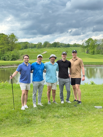 five people posing on a golf grreen