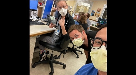 Emergency medicine residents working and smiling at their hospital desks.