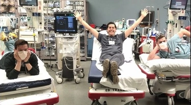 Three emergency medicine residents posing on beds in the ER room.