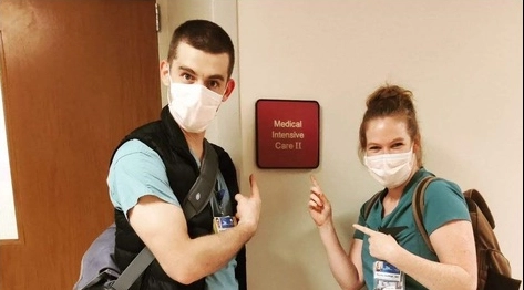 Two emergency medicine residents pointing at a hospital sign.