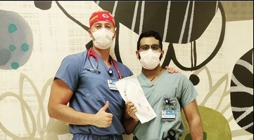 Two emergency medicine residents posing in front of hospital mural.