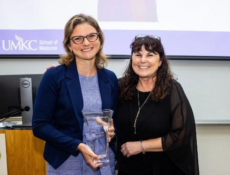 A faculty member receiving an award while smiling.