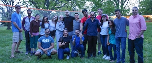 IM residents and faculty pose for a group photo with a volleyball net in the background.