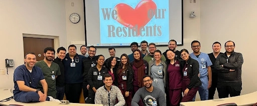 IM residents and faculty pose for a group photo in a large lecture classroom.