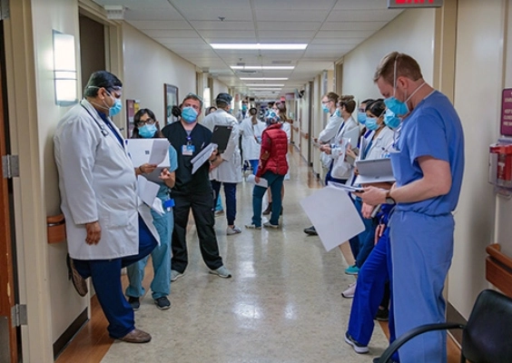 Residents and faculty converse in a hospital hallway while making their rounds.