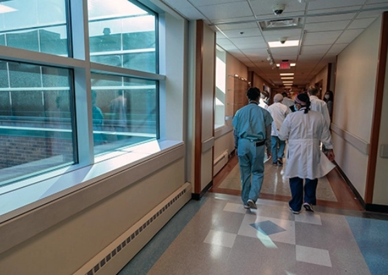 Residents walking through a hospital corridor with large windows to the outside. 