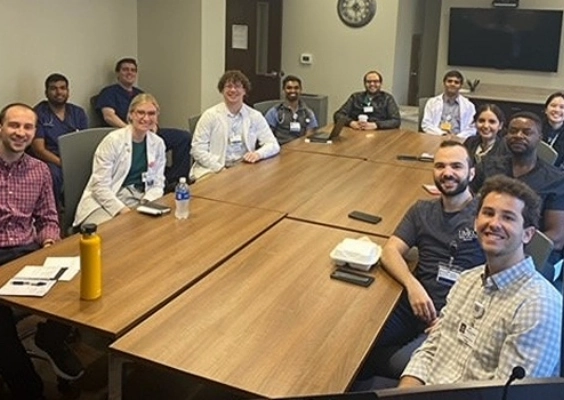 Fellows and faculty sitting around a large conference table during didactics.