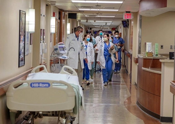 Internal medicine faculty and residents walk down a hospital hallway discussing patient care.