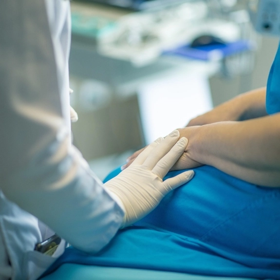 Closeup of a doctor comforting a patient by putting her hand over the patient's hand. 