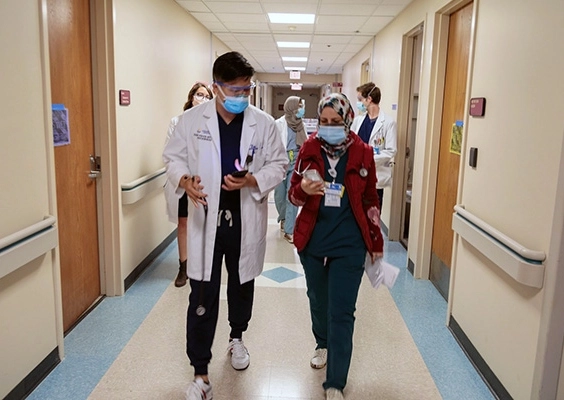 Two medical students walking down a hospital hall having a discussion.