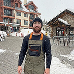 man in paved town square with snow and buildgs behind him