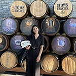 Greeshma with a stack of wine casks behind her