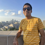 Sagar leaning on a stone wall with water and skyline behind him