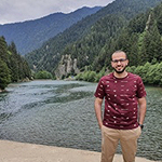 Ibrahim with a river and mountains behind him