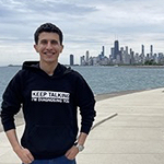 Saqr standing by water with skyline in background