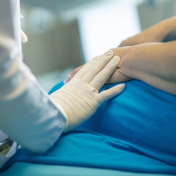 A doctor resting their hands on top of a patients hands to comfort them. 