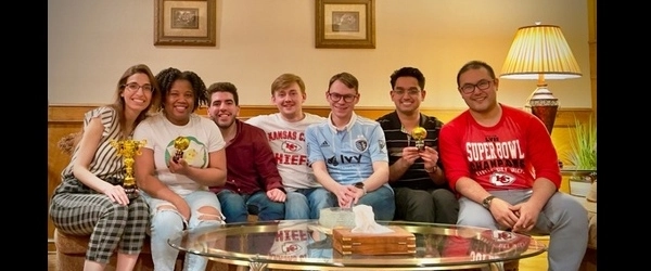 Residents sitting on a couch in someone's house smiling.