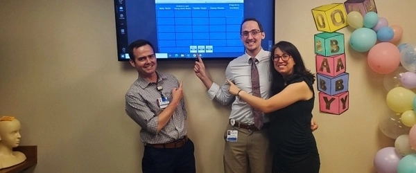 Residents smiling and pointing at a screen while celebrating during a baby shower. 