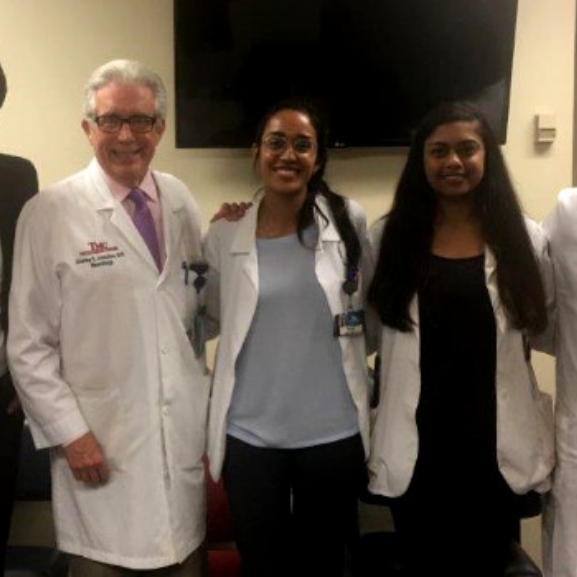 residents stand close together in white coats, smiling at camera