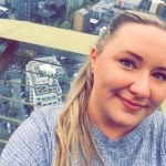 Portrait of Preslie White Hammonds, OBGYN resident, on a skyscraper with a city in the background.